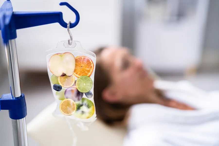 Patient receiving IV therapy with an infusion bag beside the treatment bed